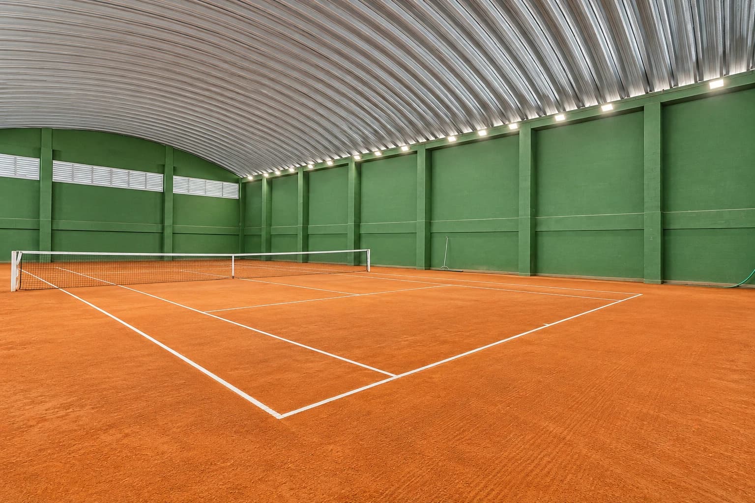 Quadra de tênis coberta do Villagio Monte Bianco, com piso de saibro e paredes verdes